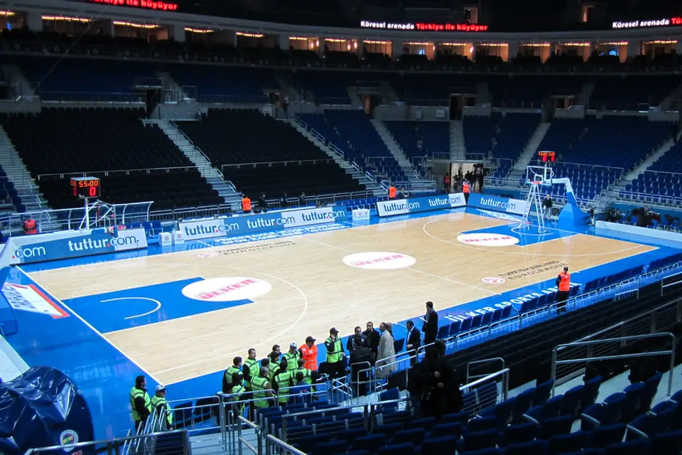 Wide view of an indoor basketball arena with blue seating